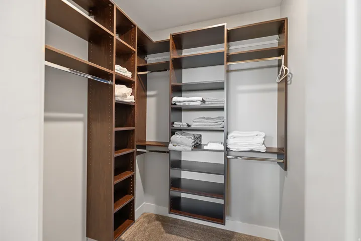 Custom closet system featuring multiple wood-finish shelves and hanging rods