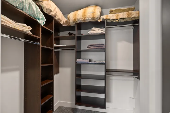 Built-in closet system featuring dark wood-finish shelving, multiple hanging rods, and integrated overhead storage