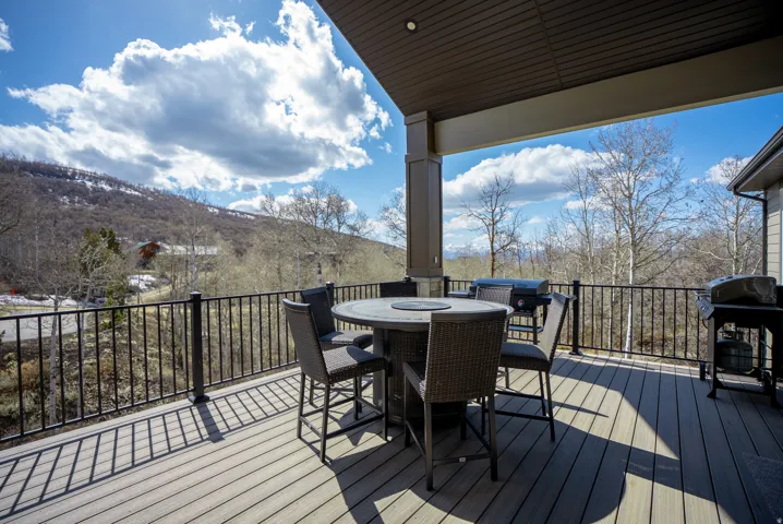 Expansive covered deck featuring a textured composite surface, black metal railing, and structural support column