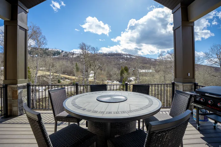 Spacious outdoor deck featuring composite decking, a metal railing, and sturdy support columns with stone accents