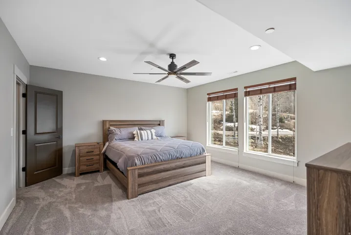 Recessed lighting, ceiling fan, two large windows, light gray wall finish, and gray patterned carpet