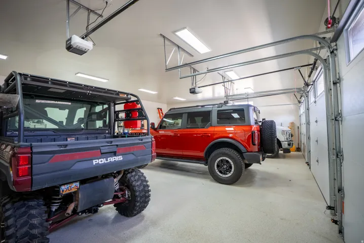 Three-car garage with multiple garage door openers, overhead lighting, and an epoxy floor