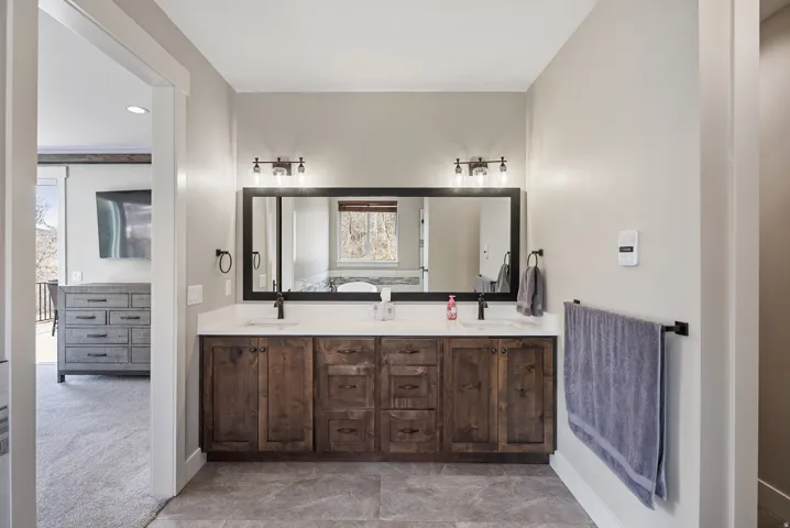 Dual sink vanity with wood-finish cabinetry, white countertop, and matte black fixtures