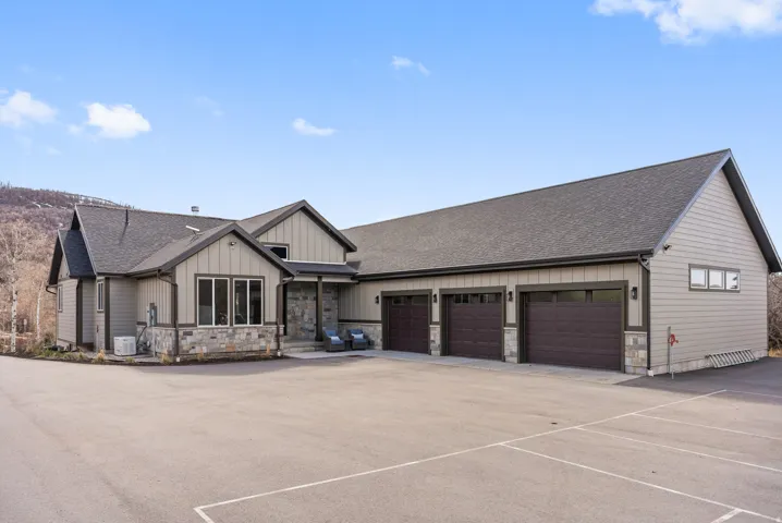 Contemporary architectural style featuring stone veneer accents, multi-pane windows, a covered entry, and a three-car garage