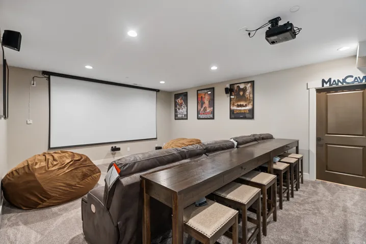 Dedicated media room featuring a ceiling-mounted projector, large retractable screen, and recessed lighting