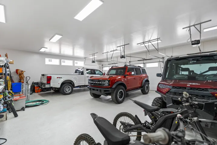 Spacious garage featuring a durable epoxy floor, multiple garage door openers, and strip lighting