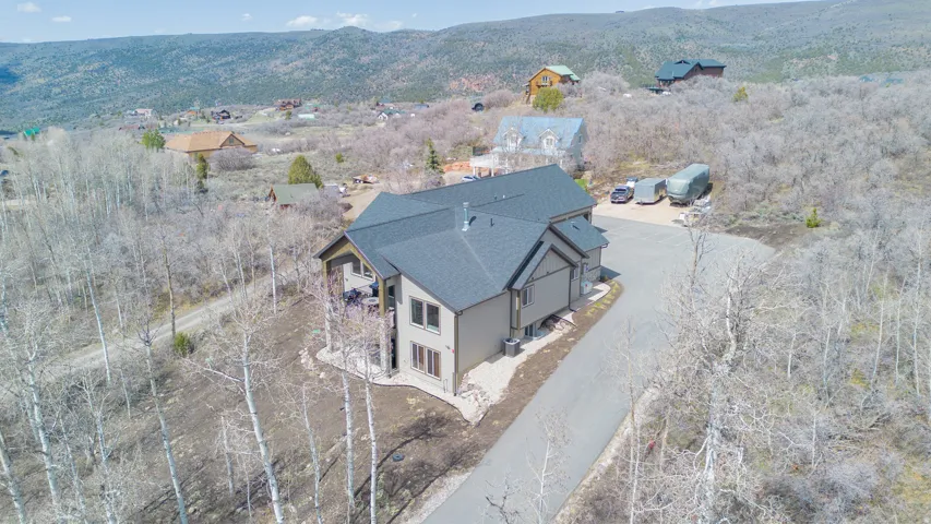 Multi-level residence with a dark shingle roof, light-toned siding, and a paved driveway
