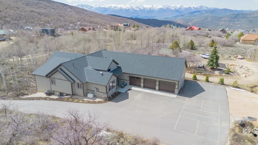 Expansive residence featuring a multi-car garage, asphalt driveway, and a basketball half-court