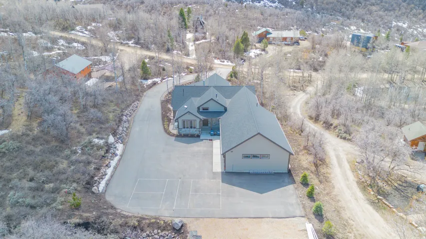 Asphalt driveway with marked court, attached garage, and a large multi-gabled roofline