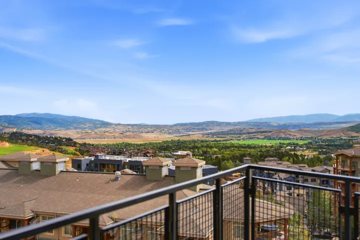 Expansive mountain and valley scenery visible from a balcony with metal railings