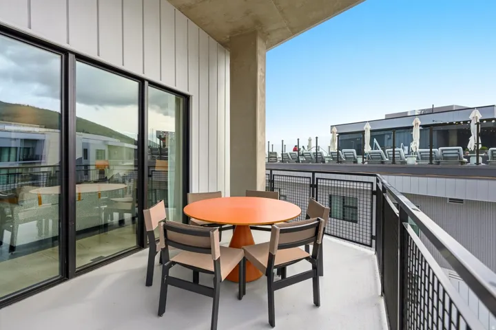Balcony with a concrete floor, black metal railing, and white vertical siding