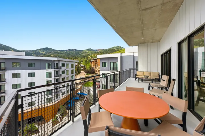 Expansive concrete balcony featuring a solid concrete ceiling, modern black metal railings, and direct access to the interior via large black-framed windows