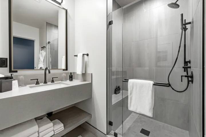 Walk-in shower with a glass enclosure, black-finish fixtures, and a rain showerhead