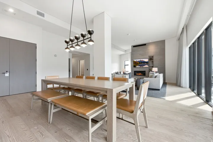 Open-concept living area with wood-finish flooring, a modern chandelier, and a built-in fireplace feature wall