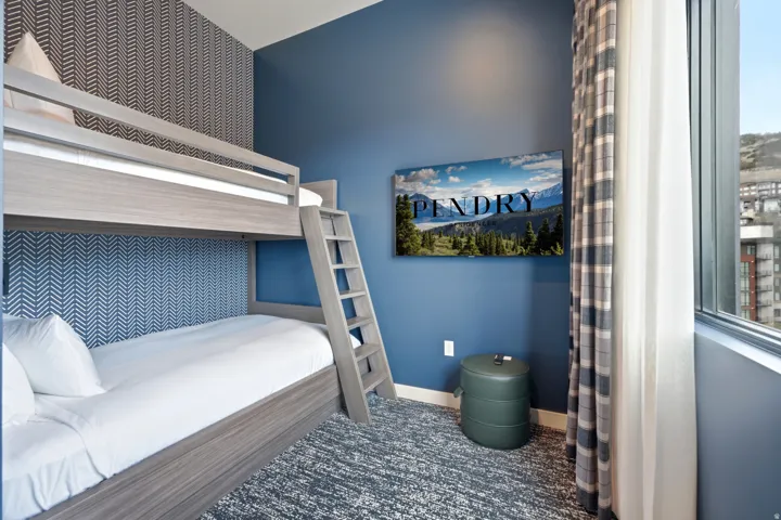 Wood-finish bunk beds with integrated ladder, a full-height window, a patterned accent wall, and patterned carpeting