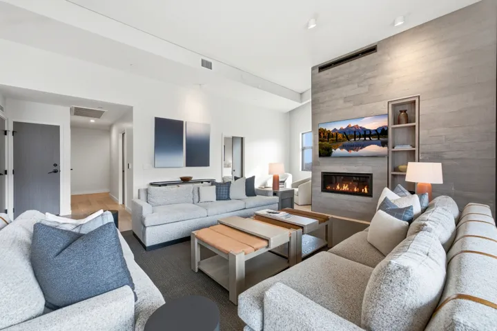 Spacious living area featuring a linear fireplace, built-in shelving, vaulted ceiling, and wood-finish flooring