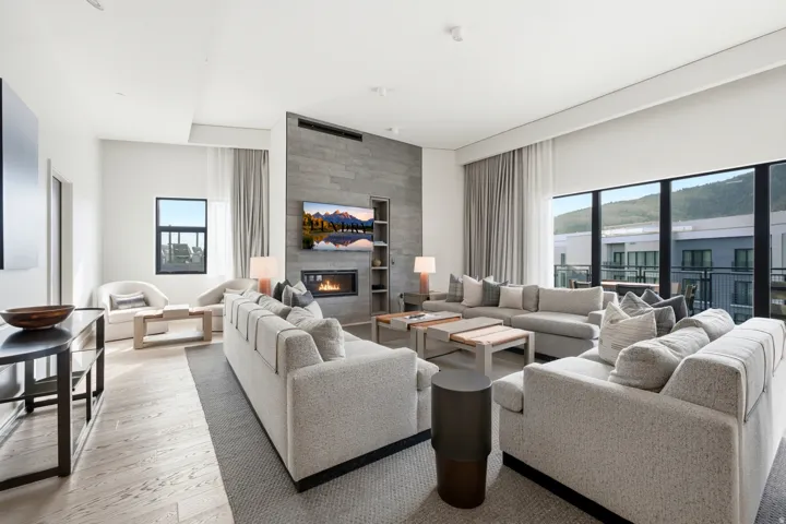Expansive living area with wood-finish flooring, a linear electric fireplace, and a stone-clad accent wall