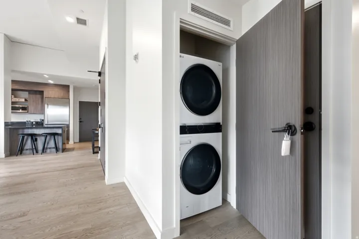 Wood-finish flooring, full-size stacked laundry appliances, recessed lighting, stainless steel refrigerator, and integrated kitchen cabinetry