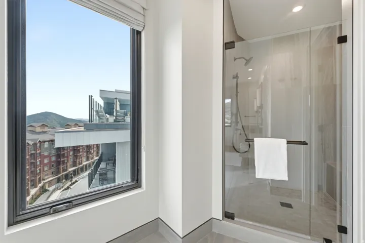 Walk-in shower with clear glass enclosure and rainfall showerhead