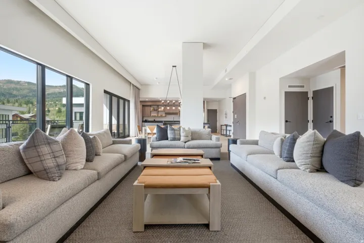 Spacious open-concept living area with large windows, recessed lighting, and durable carpet flooring
