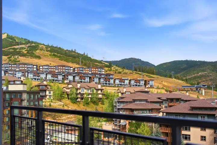Balcony with black metal railing overlooking a mountainous landscape with multiple residential structures and a ski lift infrastructure