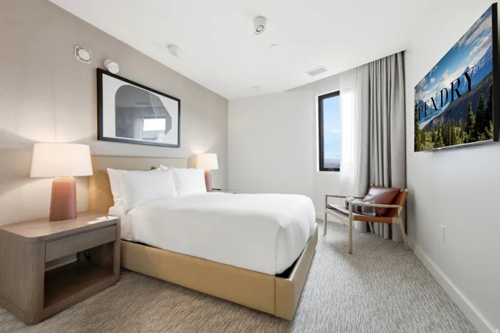 Textured accent wall, recessed lighting, and a single window with curtain panel