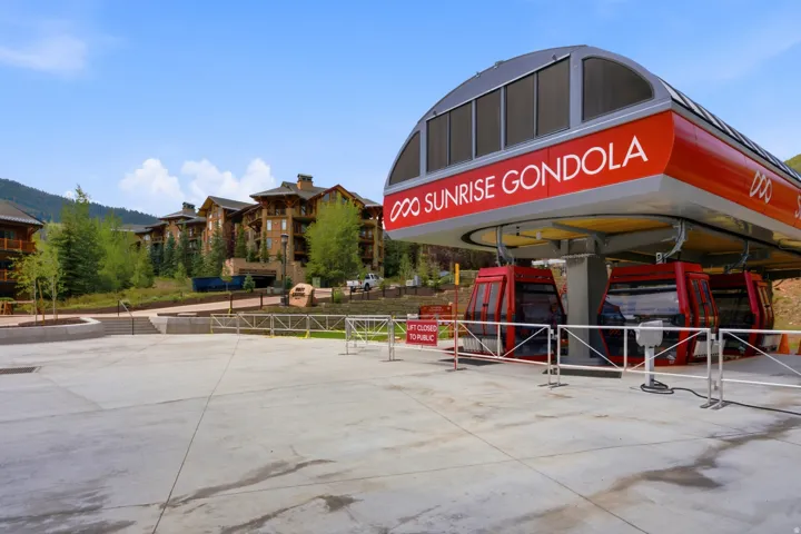 Gondola station with multiple gondola cars, featuring a concrete platform and surrounding landscaping