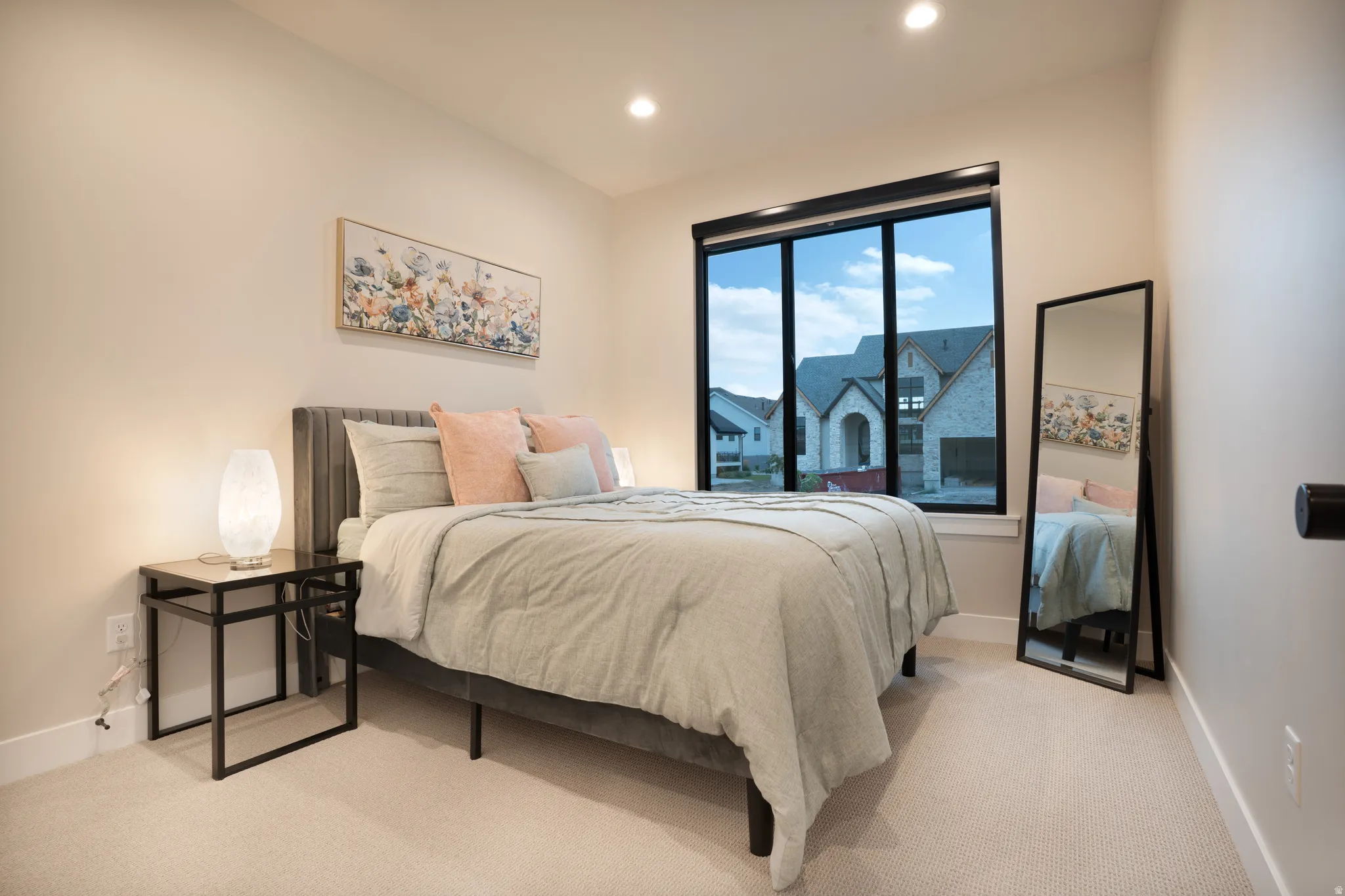 Neutral-toned carpeting, recessed lighting, and a large window with black trim