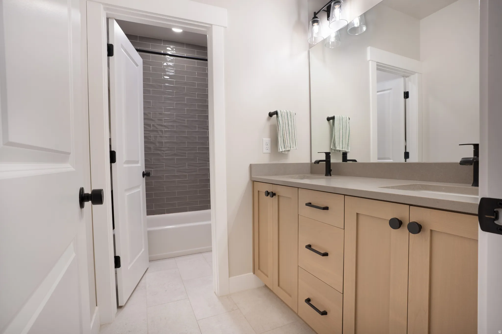 Dual vanity with light wood-finish cabinetry and matte black hardware