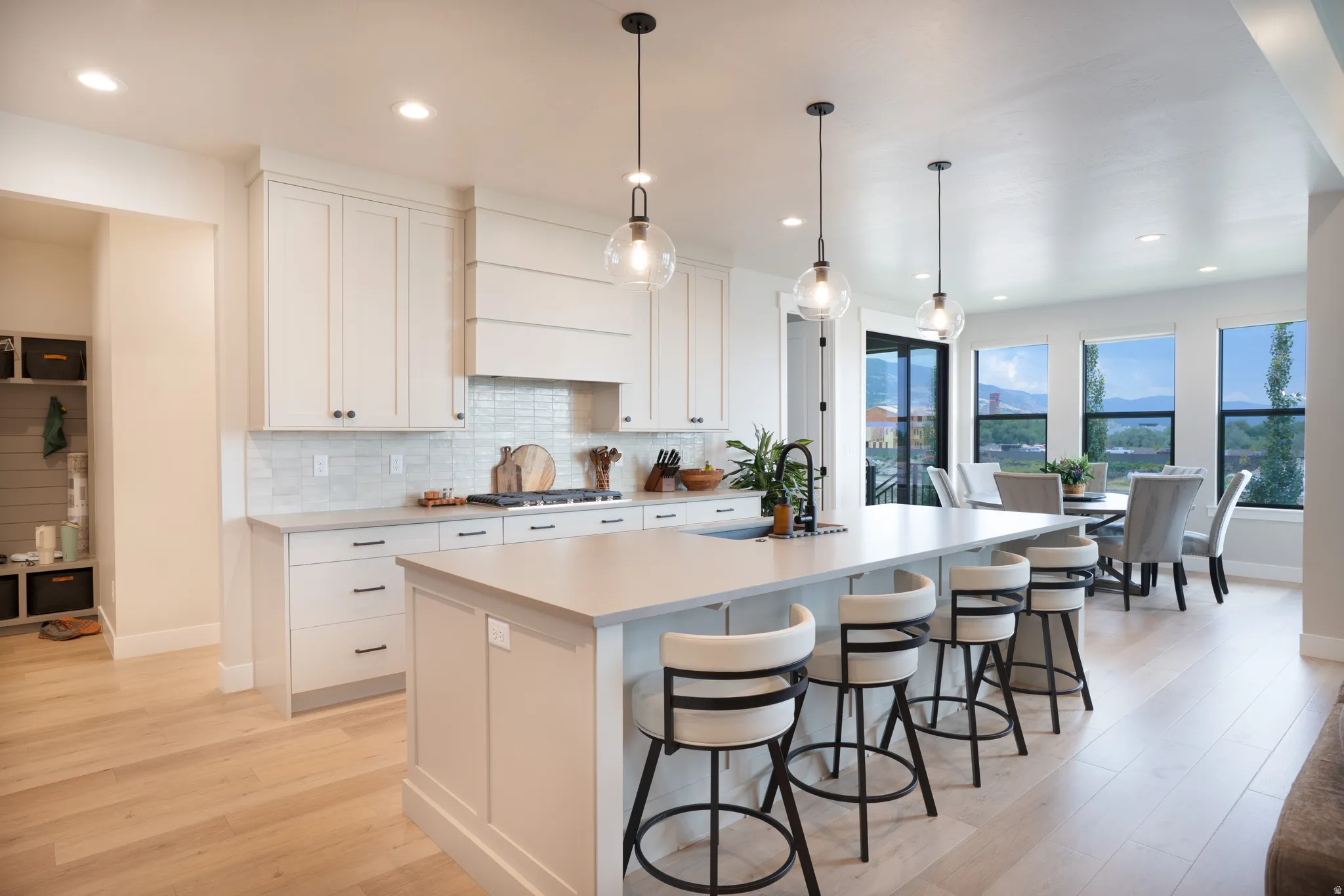 Kitchen featuring white cabinetry, light countertops, a tile backsplash, and wood-finish flooring