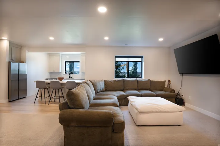 Open concept living area featuring recessed lighting, a built-in kitchen island with seating, a large wall-mounted television, and a window with exterior views
