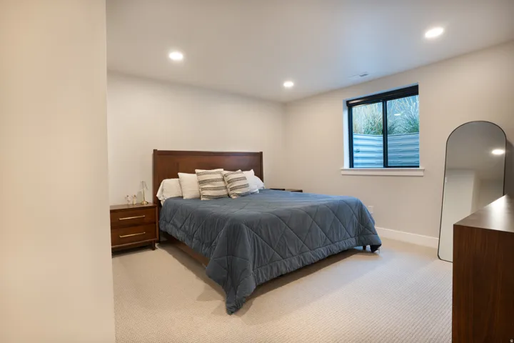 Recessed lighting, light neutral wall color, and a window with a metal window well