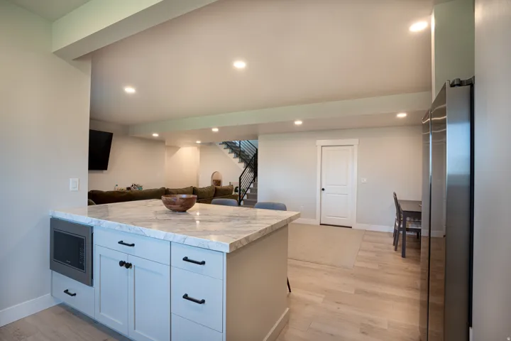 Kitchen island with integrated microwave, stainless steel refrigerator, and wood-finish flooring