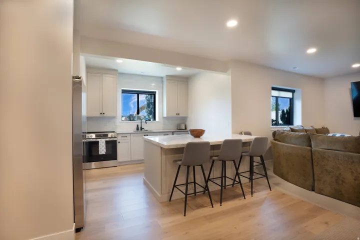 Kitchen featuring light cabinetry, stainless steel appliances, a white subway tile backsplash, and an island with seating