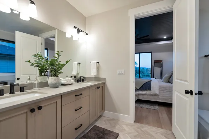 Dual vanity with light wood-finish cabinetry, black hardware, and light-toned countertops
