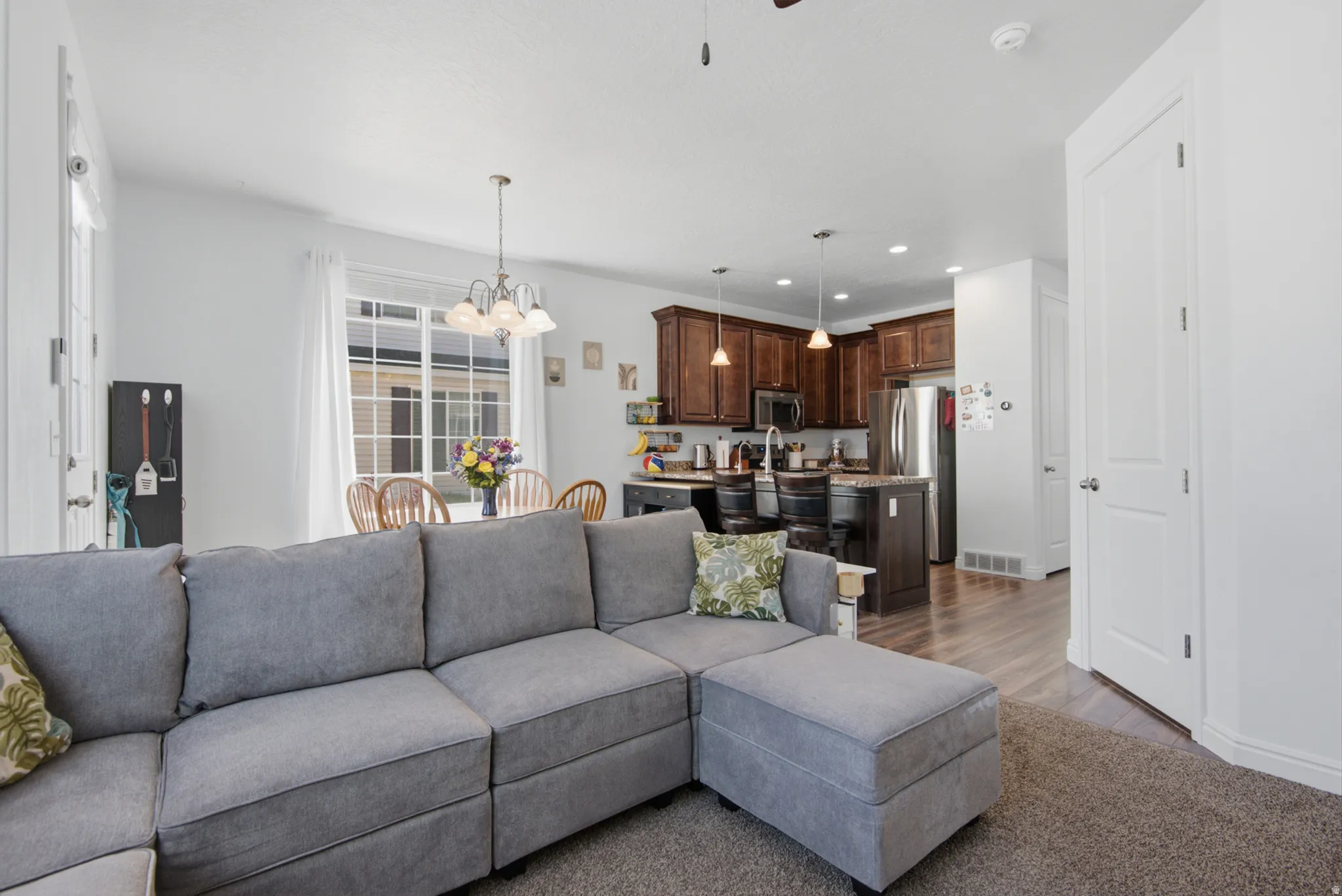 Open concept living space with wood-finish flooring, recessed lighting, and a kitchen featuring dark wood cabinetry and stainless steel appliances