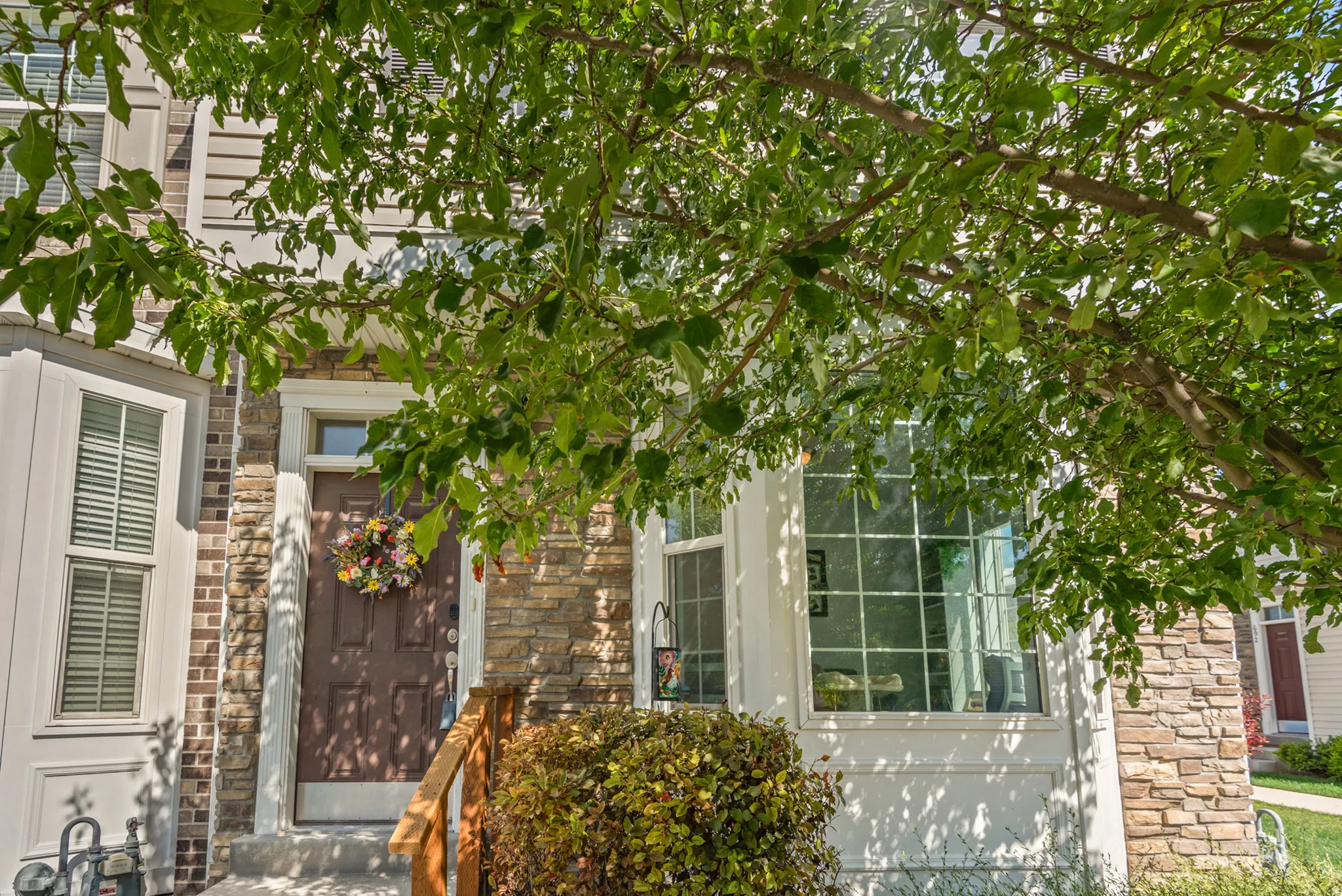 Architectural facade featuring a combination of brick and stone cladding, an entryway with a transom window, and a prominent bay window with grid-patterned panes