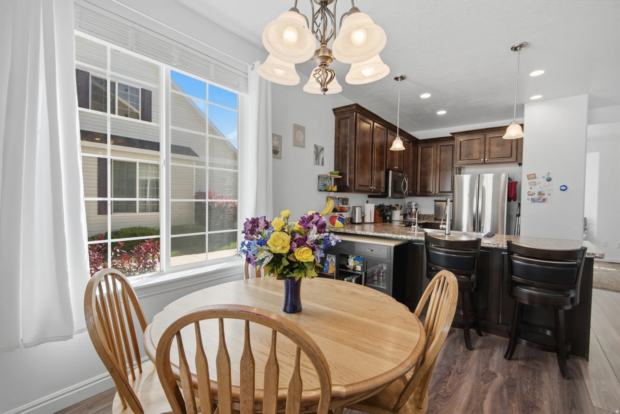 Open-concept kitchen and dining area featuring rich wood cabinetry, stainless steel appliances, a kitchen island with seating, and wood-finish flooring