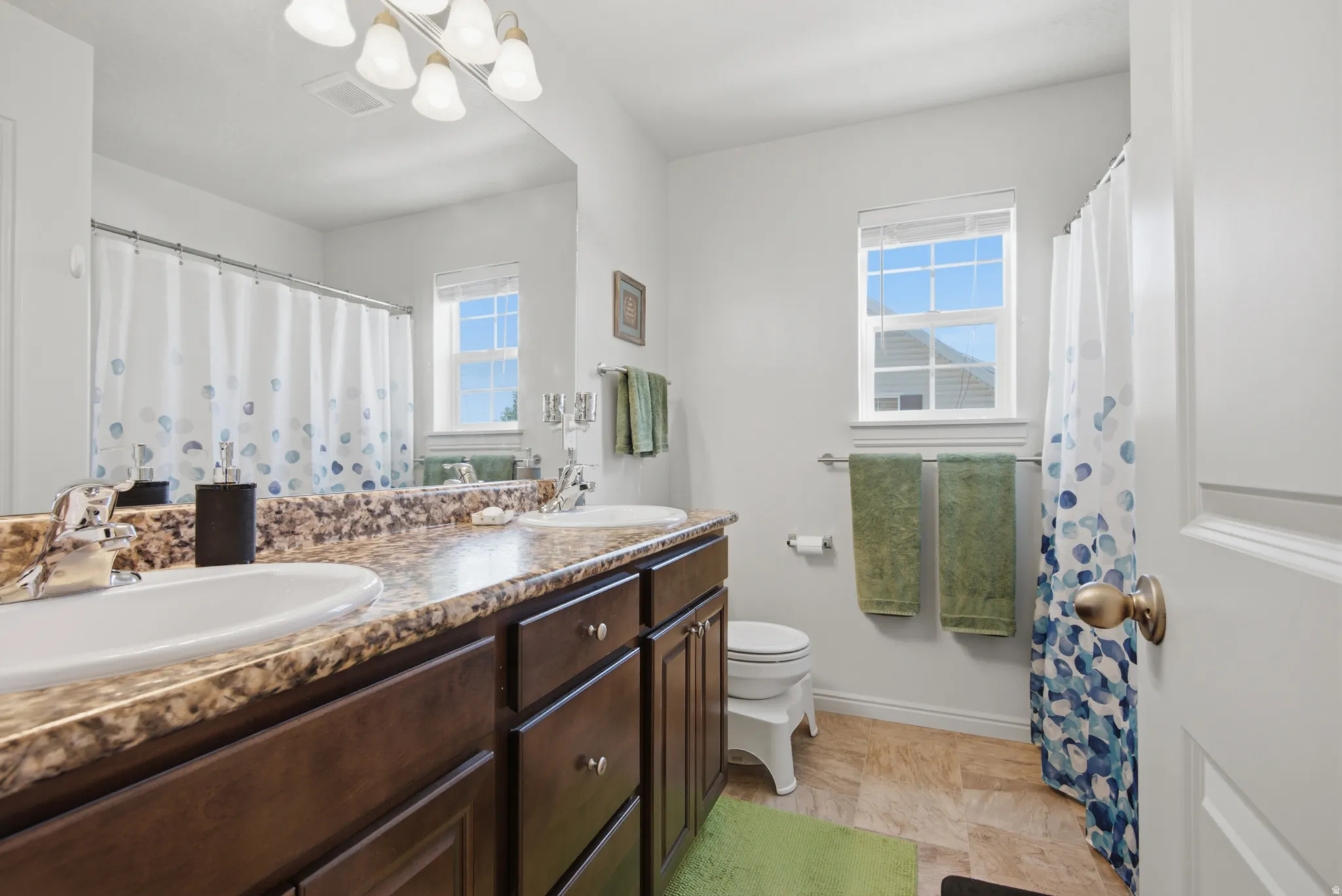 Double vanity with integrated sinks, wood-finish cabinetry, and a large mirror