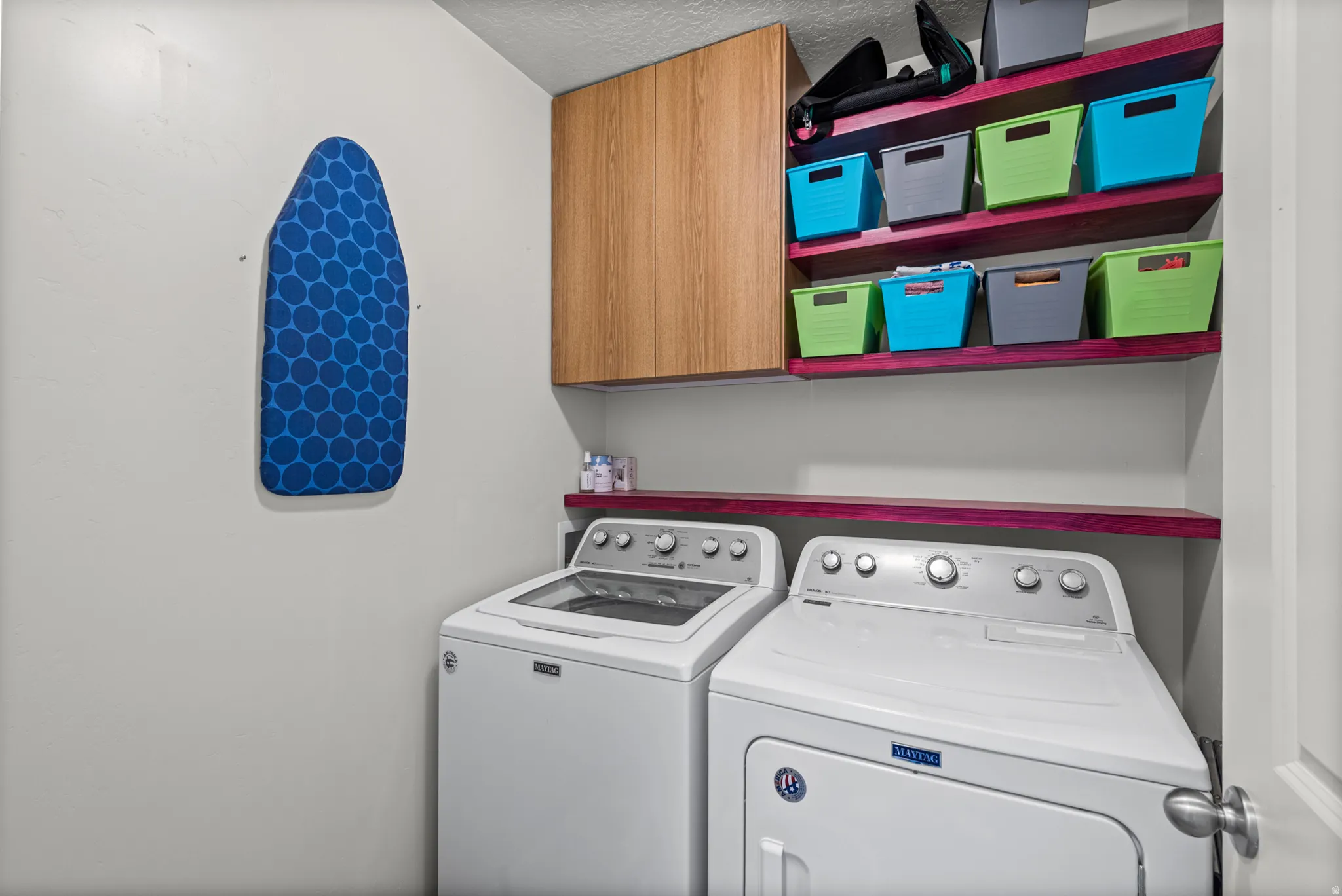 Laundry area featuring a top-load washing machine, front-load dryer, and wall-mounted shelving