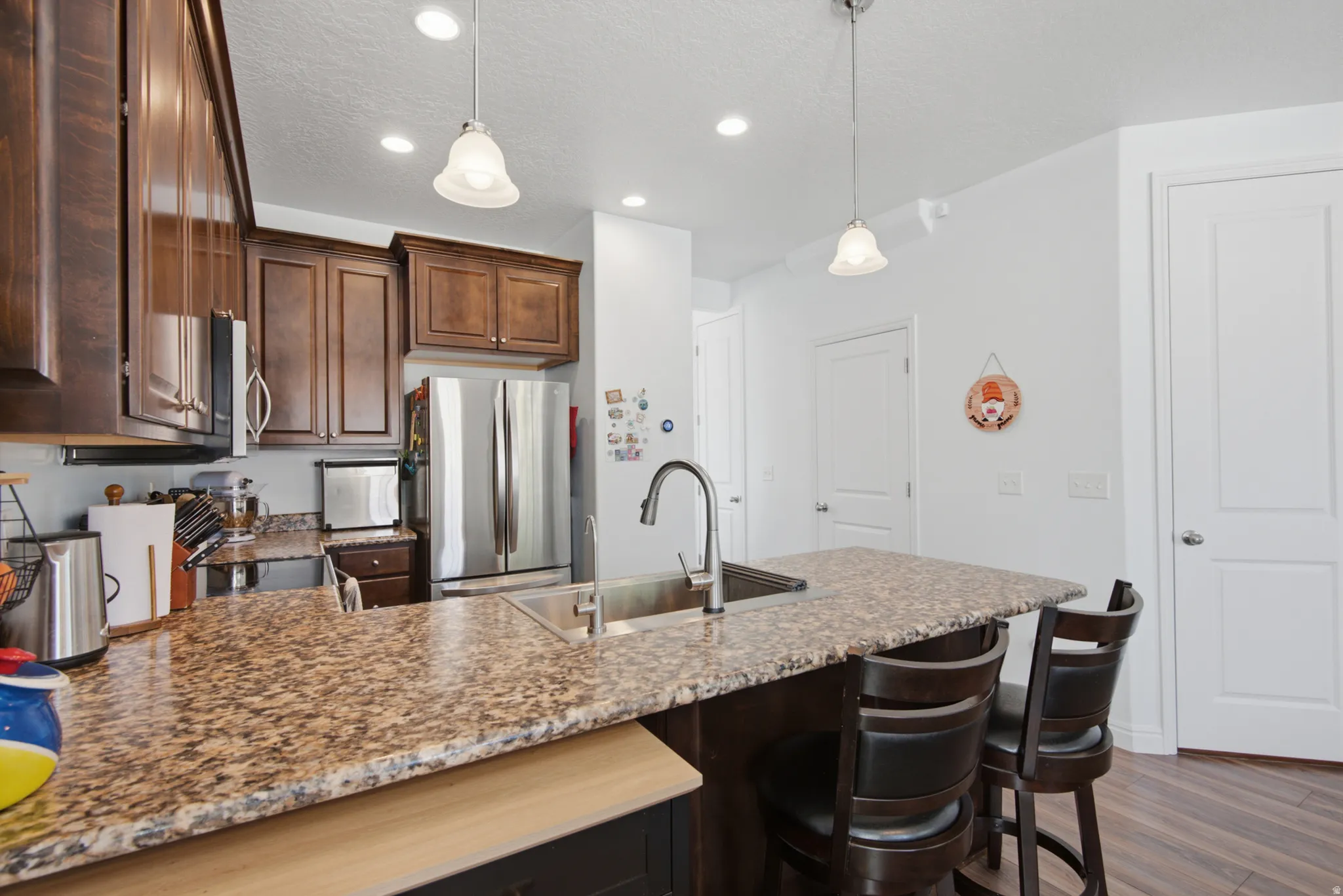 Modern kitchen featuring rich wood cabinetry, stainless steel appliances, and a spacious granite-topped island with seating for multiple guests