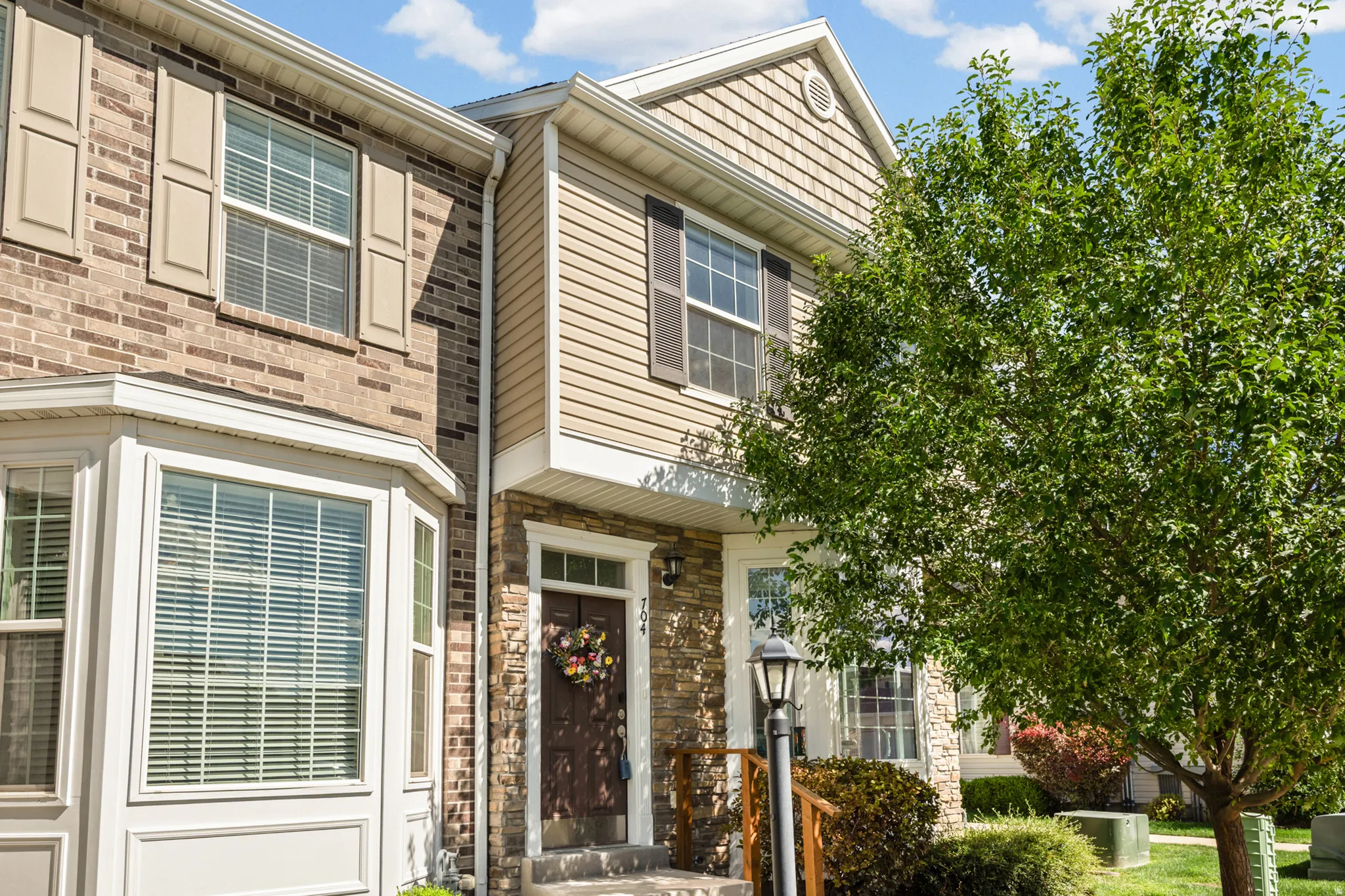 Brick and siding exterior featuring a prominent bay window, decorative shutters, and stone accents