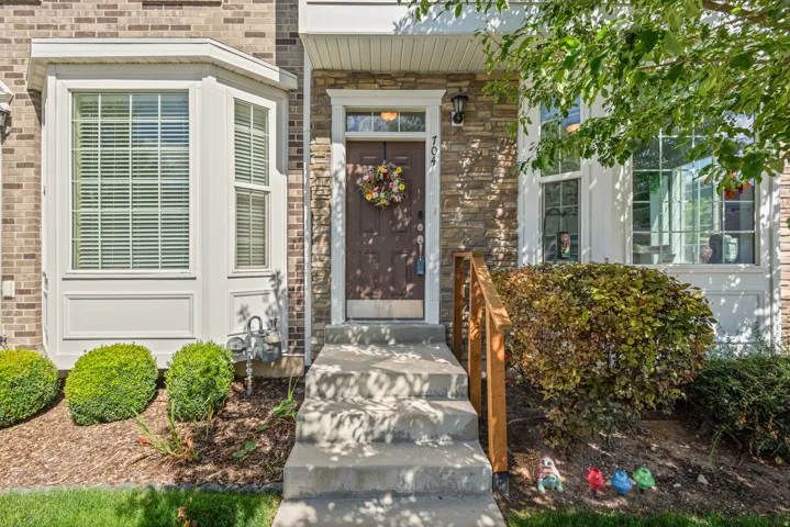 Brick and stone facade with a bay window, concrete steps, and a wooden handrail