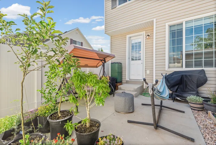 Concrete patio area with a white privacy fence, light-colored siding, and a glass-paneled exterior door