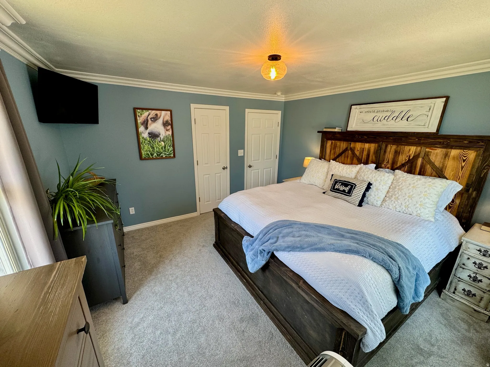 Large spacious Master Suite. Textured carpeting, wood-finish bed frame, crown molding, double doors, and a ceiling-mounted light fixture