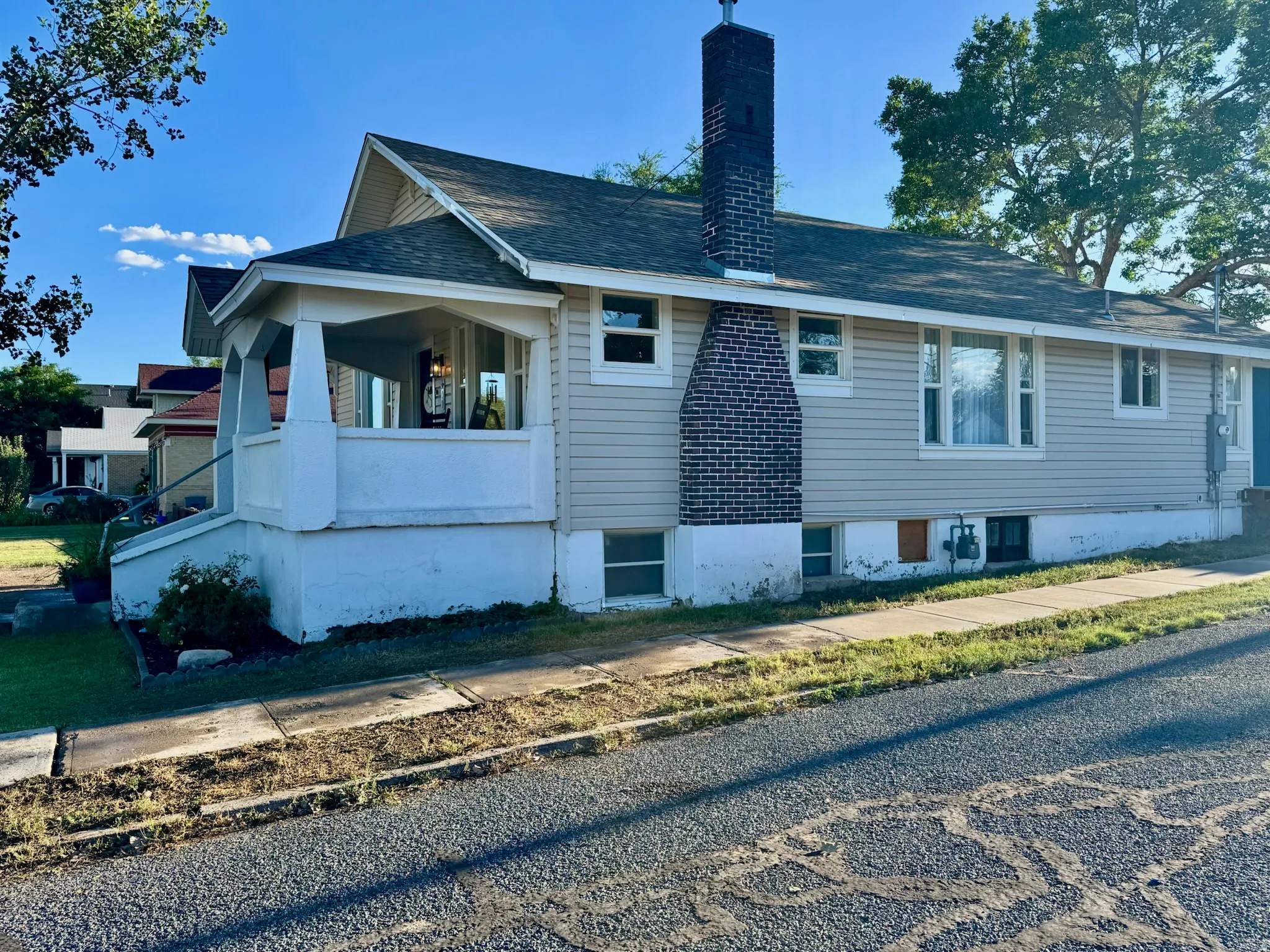 Siding exterior with a covered front porch, brick chimney, and visible foundation