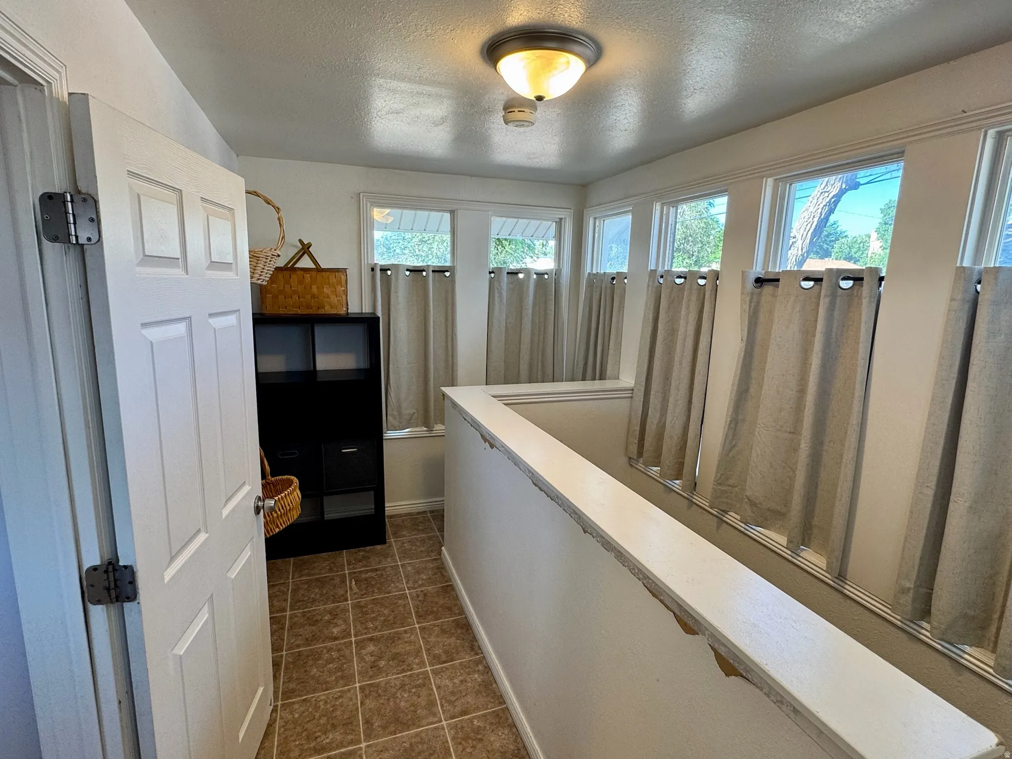 Mud room. Multiple windows providing natural light, semi-flush mount ceiling light fixture, and tiled flooring