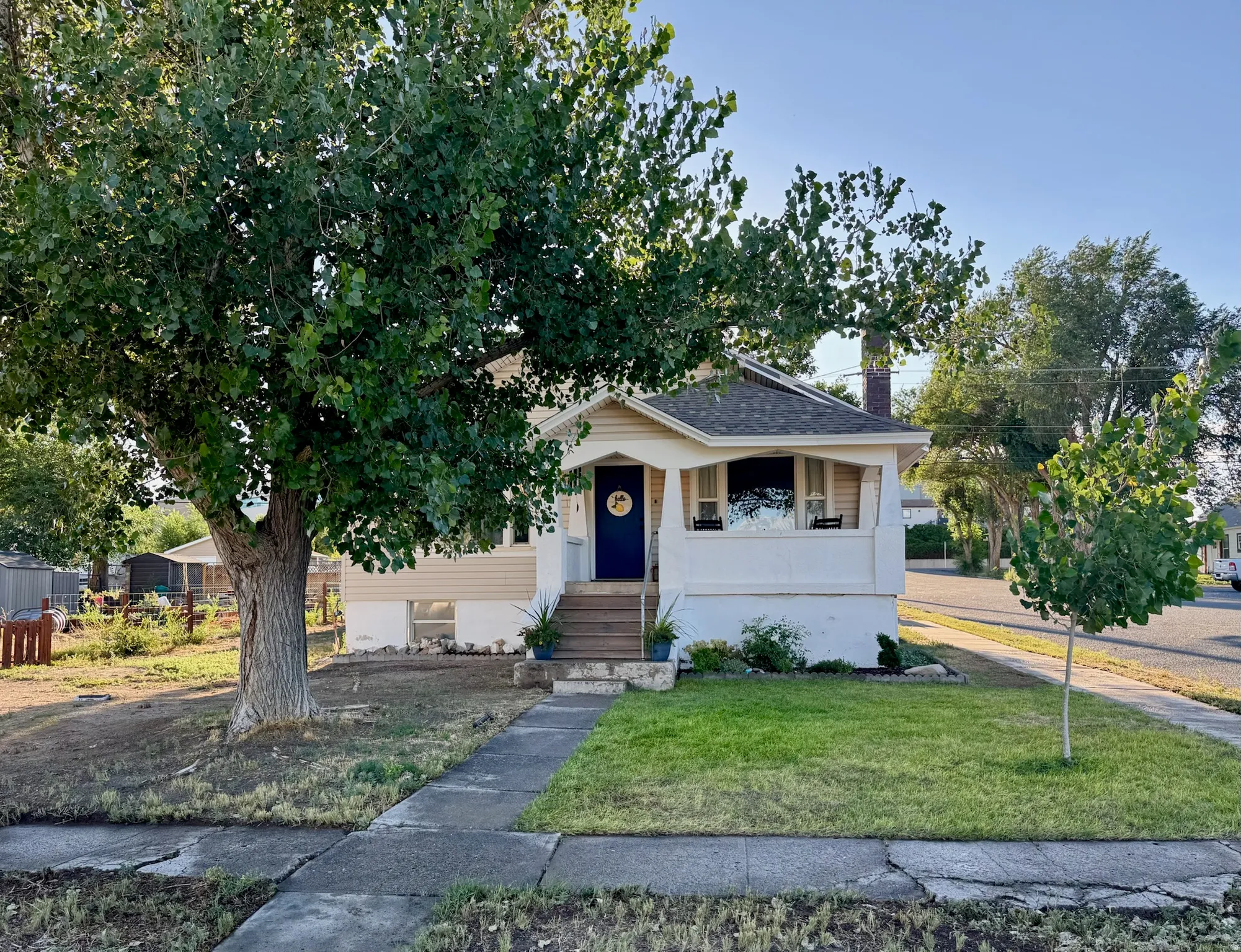 Front porch with white railing, light-colored siding, and a contrasting blue entry door