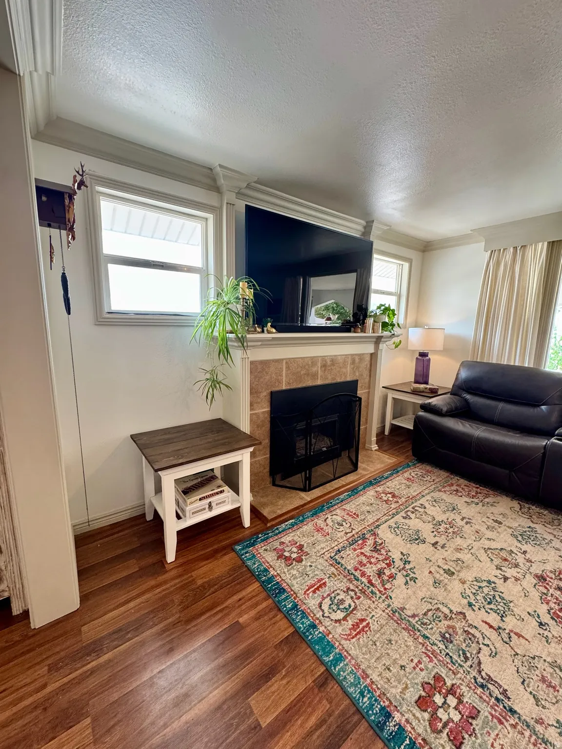 Warm wood-finish flooring complements the tiled fireplace surround. Fireplace is gas insert.