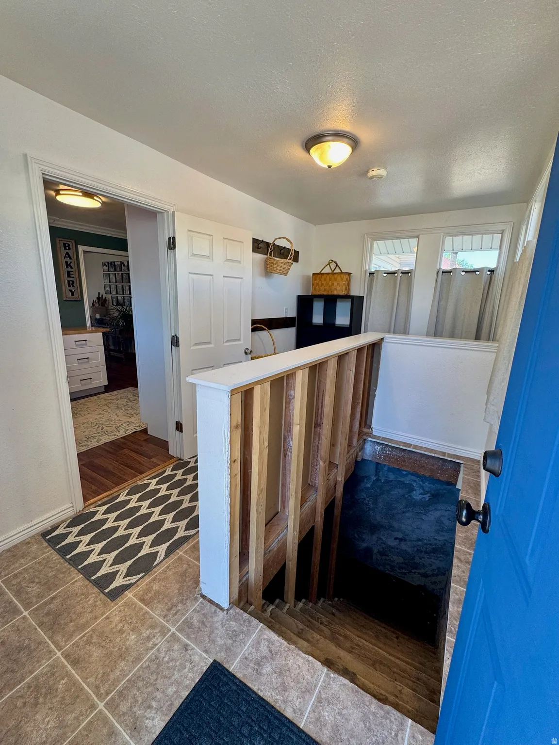 Back Entryway featuring tile flooring, a staircase with wood railing, and an interior door with a white finish